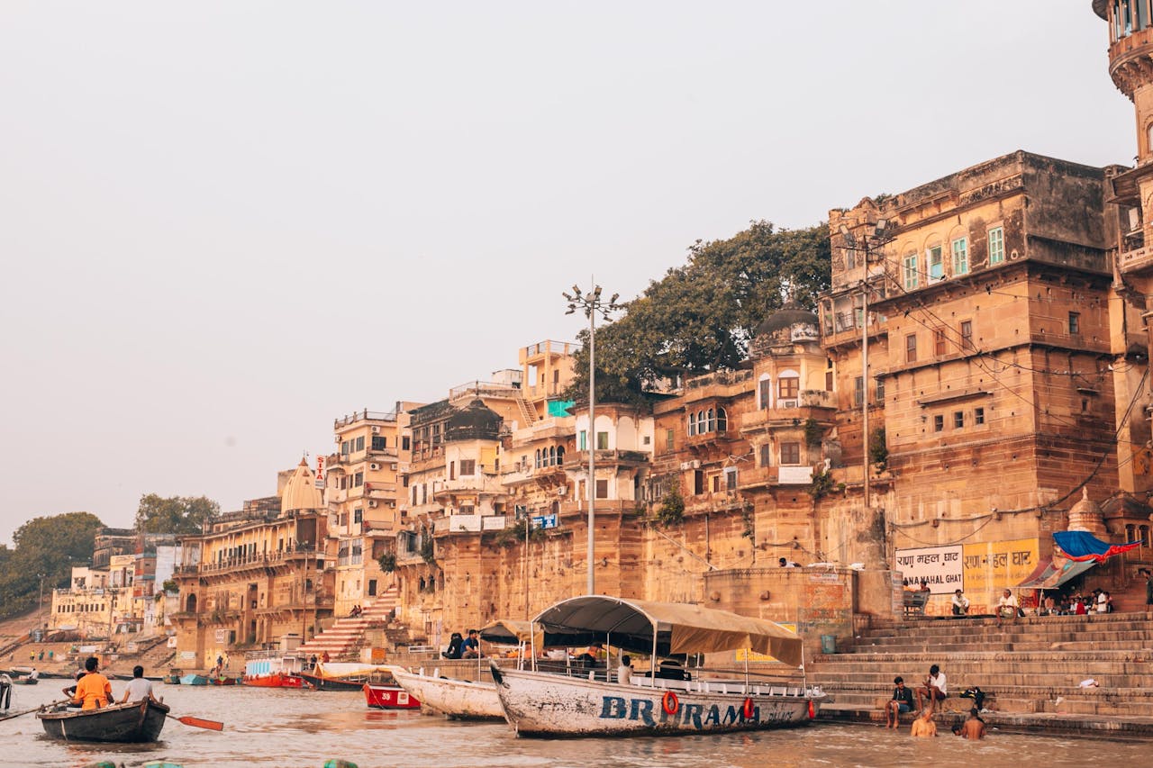 Picturesque view of Varanasi ghats along the Ganges River with bustling boats and ancient architecture.